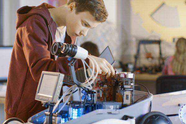 Boy Works on a Fully Functional Programable Robot with Bright LE Boy Works on a Fully Functional Programable Robot with Bright LED Lights for His School Robotics Club Project.