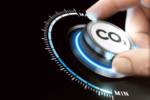Reduce Carbon Dioxyde Footprint. CO2 Removal Man turning a carbon dioxyde knob to reduce emissions. CO2 reduction or removal concept. Composite image between a hand photography and a 3D background.